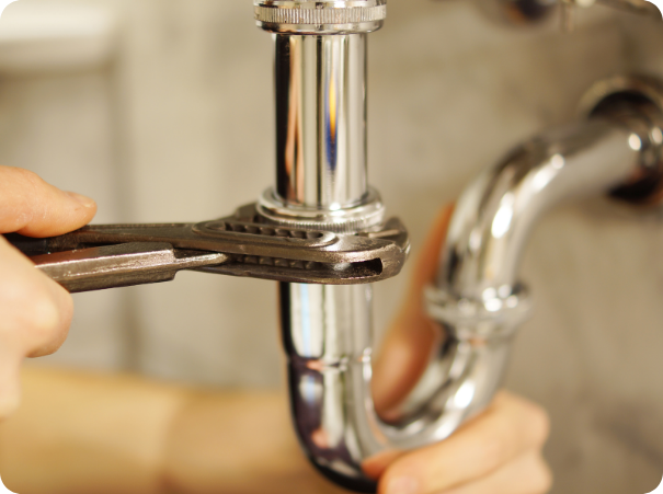 Plumber using a wrench to tighten a sink drain pipe during residential plumbing repair and installation service.